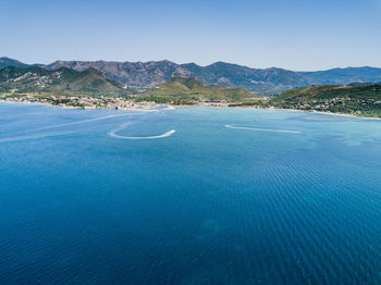 Scenic view of sea and mountains against clear blue sky