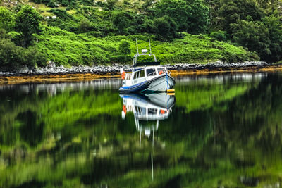 Boat moored on lake against trees