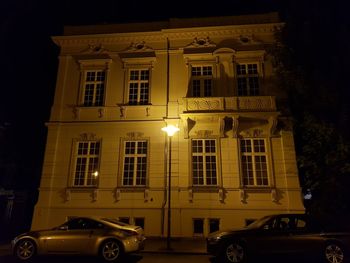 Car on illuminated street against building at night