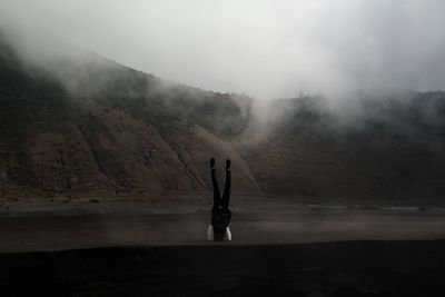 Woman standing on mountain in foggy weather
