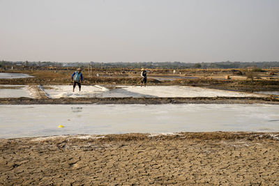 People working on beach against clear sky