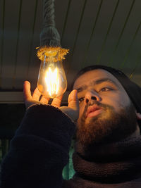 Close-up of young man holding illuminated lighting equipment