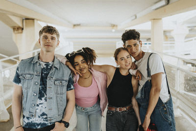 Portrait of fashionable young male and female friends posing at parking garage