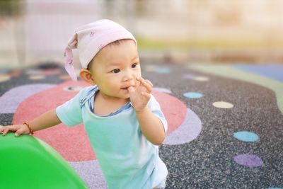 Close-up of cute baby girl looking away while standing at playground