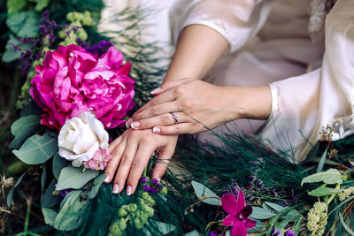 Midsection of young woman sitting by bouquet