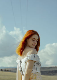 Young woman standing against sky