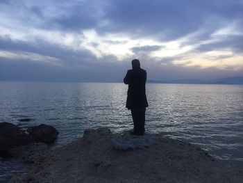 Rear view of silhouette man looking at sea against sky