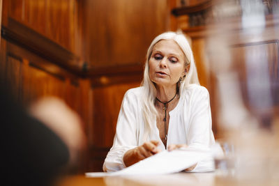 Confident female lawyer sitting with contract document in board room