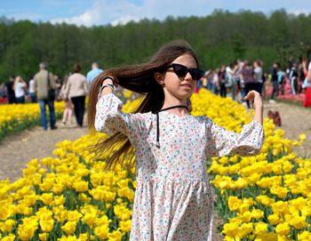 Young woman standing by yellow flowers on field