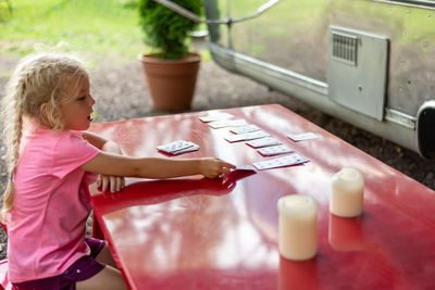 Little girl playing cards outside at a campsite
