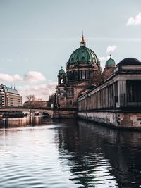 Building by river against sky in city