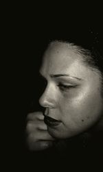 Close-up of young woman against black background