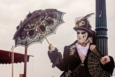 Man holding umbrella against sky