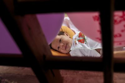 Happy child on bed seen through window at home