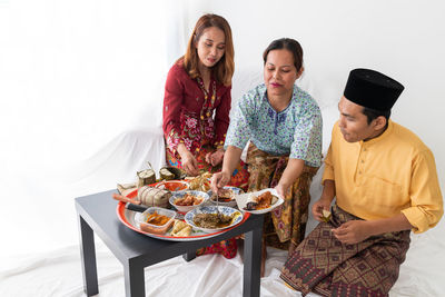 Malay family celebrates end of ramadan, in traditional dress, eating traditional cuisines.
