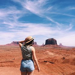 Rear view of woman wearing hat while standing against landscape