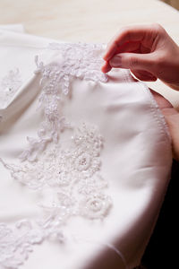 Close-up of hand sewing lace on wedding dress