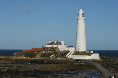 Lighthouse by sea against sky