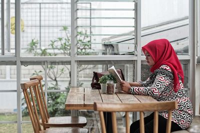 Woman reading book at table in restaurant