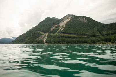 Scenic view of sea by mountains against sky