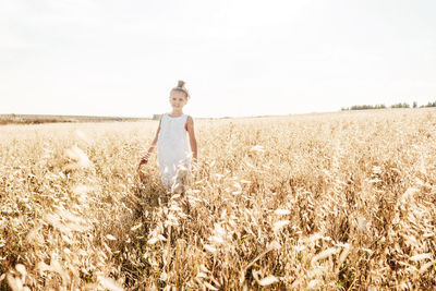 Portrait of cute girl standing in farm against sky