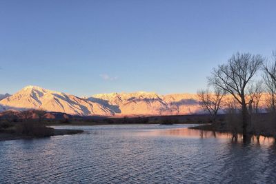 Scenic view of river by mountains against clear sky