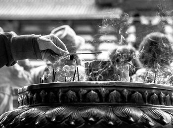 Cropped hand holding incense at temple
