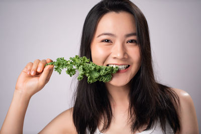 Portrait of young woman holding ice cream against white background