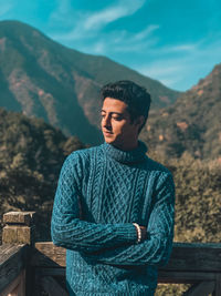 Young man standing against mountains