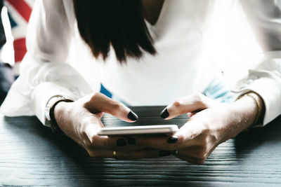 Close-up of woman using smart phone on table