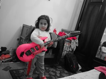 Portrait of cute girl playing guitar at home