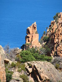 Rock formation by sea against blue sky