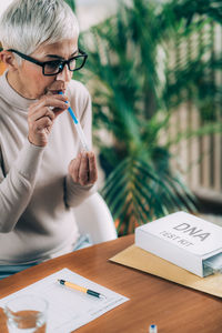 Midsection of woman holding paper while sitting on table