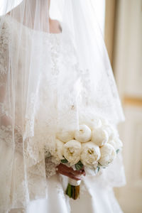 Midsection of bride holding bouquet