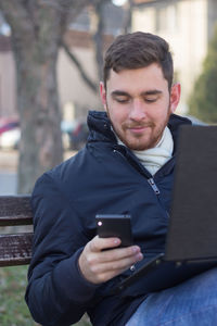 Mid adult man using mobile phone while sitting outdoors