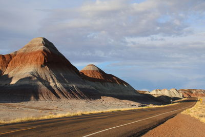 Road leading towards mountain against sky