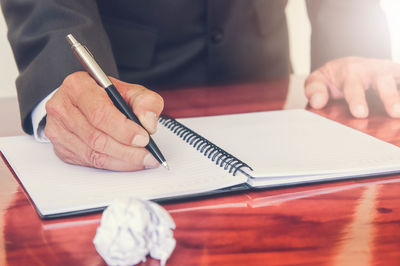 Businessman writing in diary on table at office