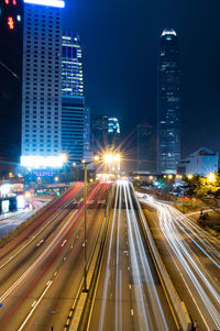 Light trails on road amidst buildings in city at night