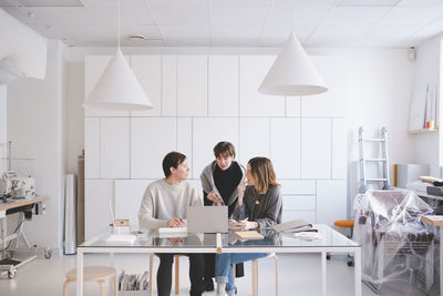 Female fashion designers discussing over laptop at desk in studio