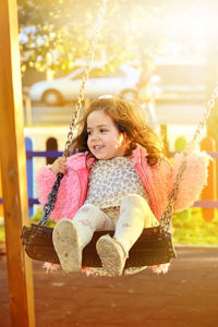 Close-up of girl sitting on swing at park