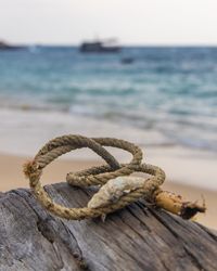 Close-up of rope on rock at beach against sky