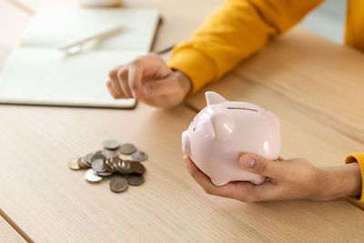 Cropped hands of man holding coins on table