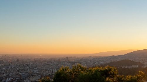 Aerial view of city buildings against clear sky during sunset