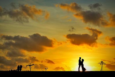 Silhouette couple photographing orange sky during sunset