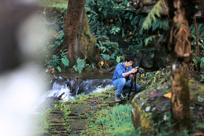 Rear view of man photographing through mobile phone in forest