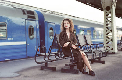 A woman sitting near a train at a train station
