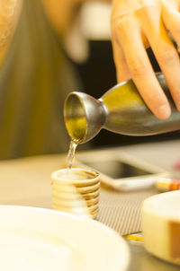 Cropped image of hand pouring hot sake from traditional flask