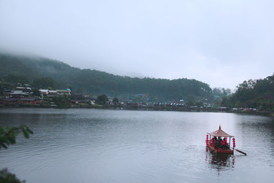 Rear view of men on boat in river against sky