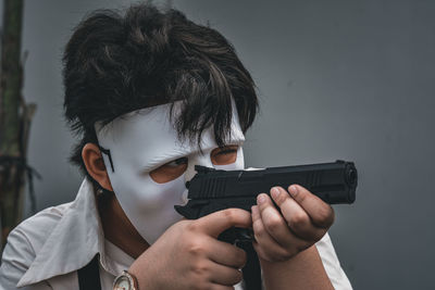 Portrait of a person wearing a mask holding up a fake gun