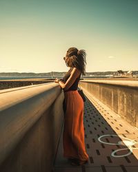 Side view of woman standing by water against sky